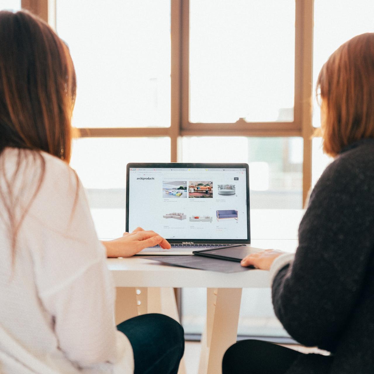 two women talking while looking at laptop computer