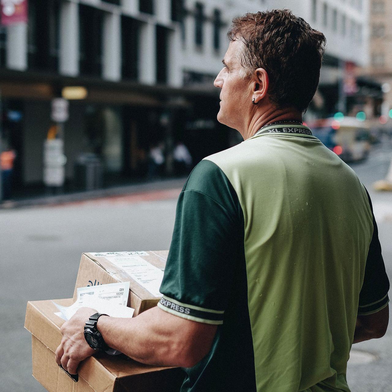 man carrying cardboard boxes during daytime